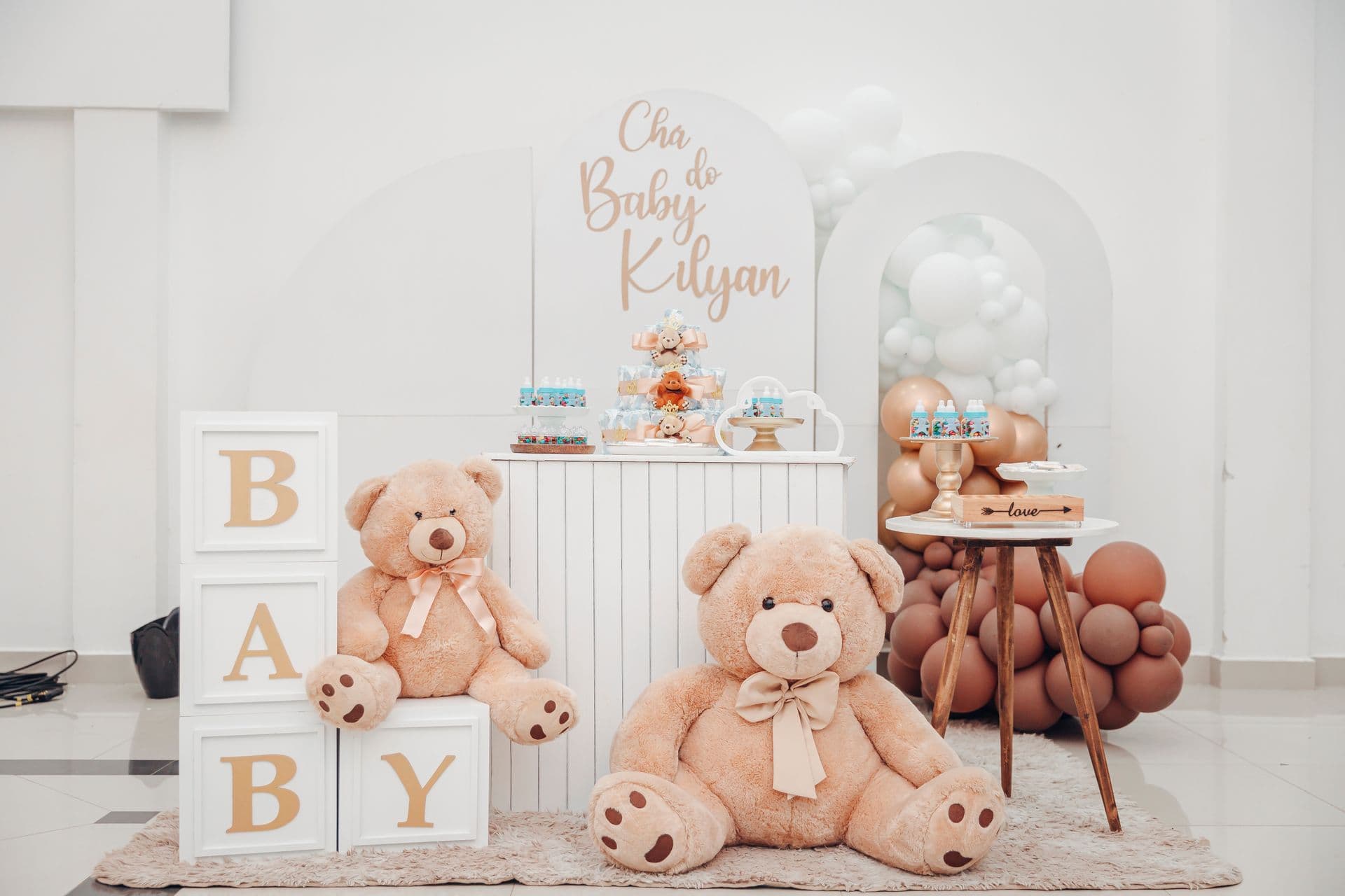 Elegant gender reveal dessert table with teddy bears and a balloon arch